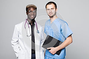 Best doctors. Two caucasian and afro american smiling doctors while standing against gray background