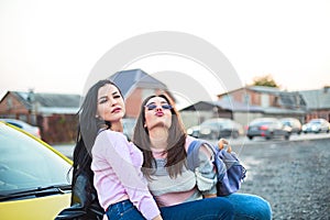 Best female friends cheering by car road trip at sunset. Happy people outdoor on vacation tour