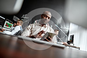 The best financial state of mind. Focused african male trader sitting by desk and studying analytical reports using