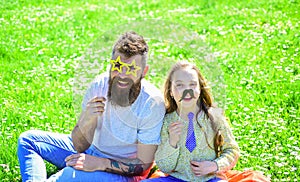 Best friends concept. Dad and daughter sits on grass at grassplot, green background. Family spend leisure outdoors