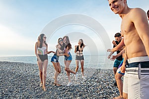 Friends dance on beach under sunset sunlight, having fun, happy, enjoy