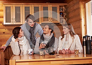 Best friends drinking hot tea in cosy kitchen at winter cottage