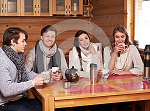 Best friends drinking hot tea in cosy kitchen at winter cottage