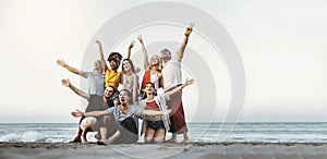 Best friends having fun together at the beach - Group of happy young people with arms up enjoying holiday outside