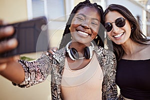 Best friends having fun and taking a selfie outdoors. Two multiethnic female friends spending time together and taking