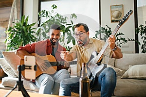 Best friends, musician jamming together, making video on social media. Playing music on guitar together at home for fans photo