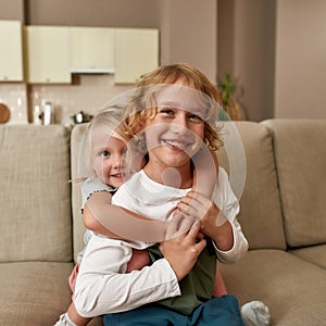 Best friends. Portrait of happy siblings, little boy and girl smiling at camera, embracing each other while sitting on a