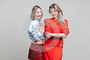 Best friends. Portrait of two fashion female models in stylish casual clothes standing together, indoor studio shot isolated on