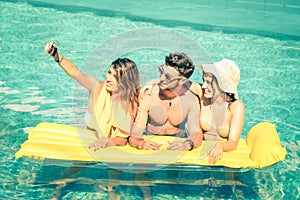 Best friends taking selfie at swimming pool with yellow airbed