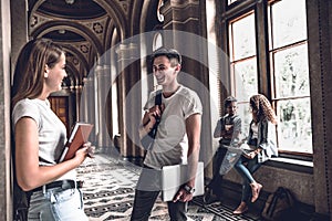 The best friends.Young smiling students standing in the university hall and speak with each other