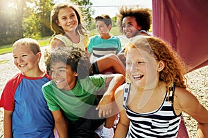 The best fun happens a the park. a group of diverse and happy kids hanging out together outside.