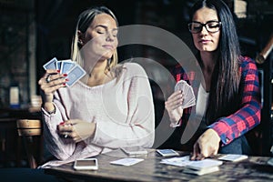 Best girls friends playing game card at home.