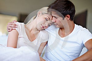 The best kind of comfort zone. Shot of a sad young woman being comforted by her husband in bed.