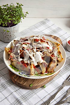 Baked potato with greens, garlic and sauces on a white plate