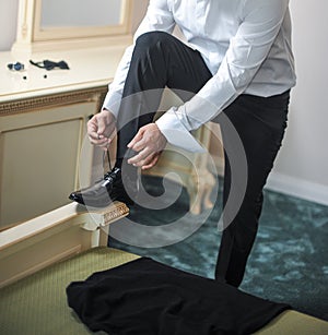 Best man getting ready for a special day. A groom putting on shoes as he gets dressed in formal wear. Groom's suit.