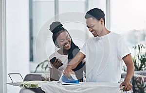 The best marriages are built on compromise and commitment. a happy young couple ironing freshly washed laundry together