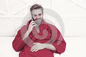 The best phone for keeping in touch. Happy man talking on mobile phone in bed. Handsome caucasian guy smiling during his