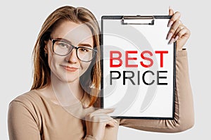 BEST PRICE. Beautiful young business woman wearing glasses holds a clipboard with mock up space isolated on gray background