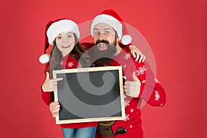 Best product to sell at Christmas. Happy family presenting product at empty blackboard. Bearded man and small child