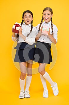 Best pupils award. Holiday celebration. Sharing gifts. Rewarding excellent pupils. Girls opening gifts yellow background