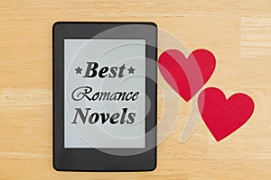 Best Romance Novels text on an e-reader on a wood desk with two hearts