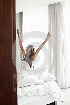 Best sleep ever. An attractive young woman stretching in bed after waking up.