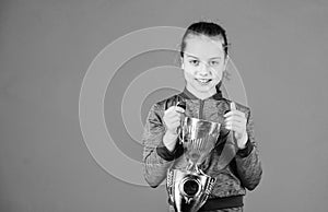 She is the best. Small girl holding silver cup. Little child with cup shaped sports trophy. Cute athlete being awarded