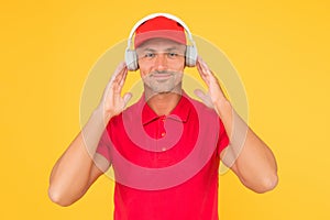 Best sounding headphones. Happy guy wear headphones yellow background. Handsome man listen to music in headphones. Using