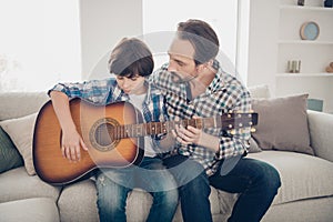 Best teacher are your relatives concept. Concentrated focused mature father helping student to learn how to play guitar