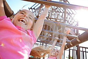 The best things in life arent things. two little girls hanging on the monkey bars at the playground.