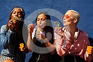 The best way to end a great day. three attractive young women sitting against a blue wall together and bonding by