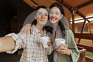 Best young caucasian female friends with cup of tea spend leisure time in countryside cottage spring