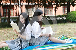 Bestie Happy cute lovely beautiful young girl high school college student enjoy free time read a book at school on grass lawn