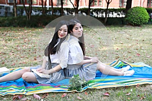 Bestie Happy cute lovely beautiful young girl high school college student enjoy free time read a book at school on grass lawn