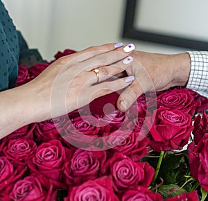 Betrothal ring on woman hand with pink bouqet of roses. Romantic event