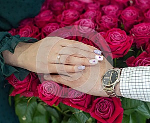 Betrothal ring on woman hand with pink bouqet of roses. Romantic event