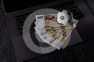Bets, sports betting, bookmaker. Soccer ball and money on a laptop`s keyboard photo