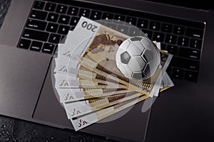 Bets, sports betting, bookmaker. Soccer ball and money on a laptop`s keyboard close-up photo