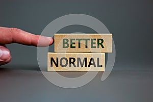 Better normal symbol. Wooden blocks with words `better normal` on beautiful grey background. Male hand. Business and better norm