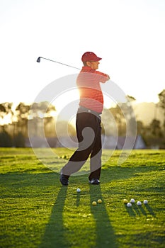 Better practice my swing before we start. A male golfer going through some practice swings before starting the round.