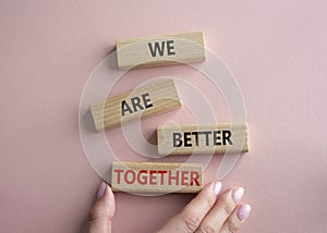 We are better together symbol. Wooden blocks with words We are better together. Beautiful pink background. Businessman hand. We