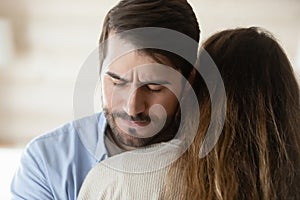 Compassionate millennial man hugging young suffering woman sharing her grief photo