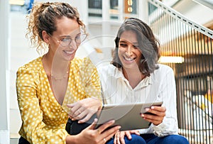 The better you work together the better the results. two young businesswomen using a digital tablet in a modern office.