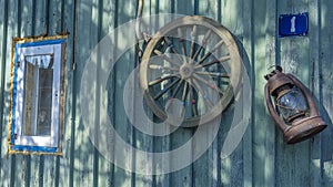 Betty lamp and spinning wheel in the background of the old log-house wall with sign nomber one. Rural retro still life.