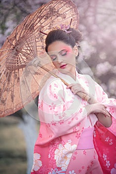 Beuatiful girl wearing japanese traditional kimono in orchard during spring