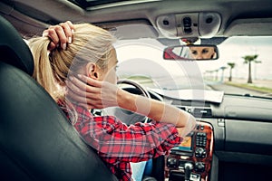 Beutiful blond girl comb her hair with a rearview mirror in car