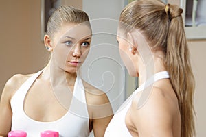 Beutiful blonde girl looking in mirror fitness gym