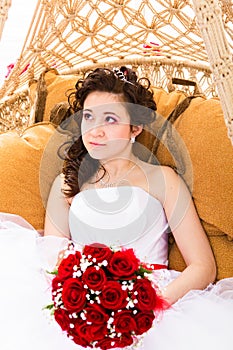 Beutiful bride in white dress holding wedding bouquet red roses