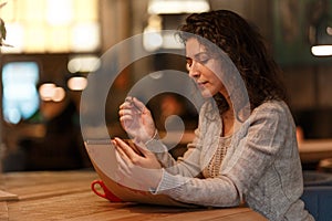 Beutiful brunette business woman make notes in her notepad in cozy restraunt. dressed in gray knitted sweather