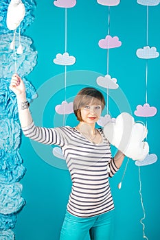 Beutiful and young caucasian girl holding white soft clouds on blue background.